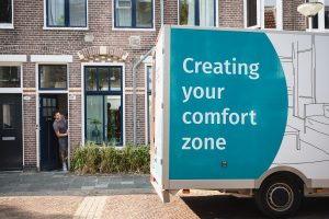 KeyPro verhuiswagen voor woning terwijl bewoner de deur opent, levering en inrichting voor expat huisvesting en comfortabele woonoplossingen